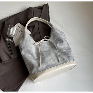 Detail of grey canvas tote bag with white bow prints and cream leather straps