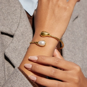 Minimalistischer goldener Armreif mit Perle und Tropfendesign am Handgelenk