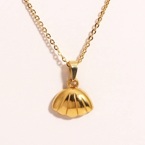 Nahaufnahme eines goldenen Muschel-Anhängers aus Edelstahl an einer feinen Gliederkette