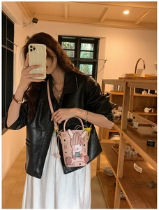 Detailed view of pink crossbody bucket bag with cartoon rabbit charm and bear patterns
