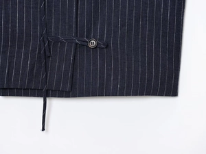 Close-up of dark blue pinstripe linen fabric with a black button and drawstring detail