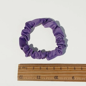 Detailed view of a purple satin scrunchie next to a ruler showing 6-7 cm diameter