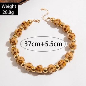 Détail de perles en peluche léopard et de sphères en métal doré sur le collier chic