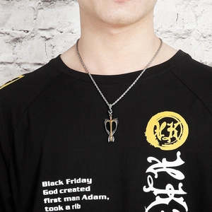 Detailed view of silver and gold arrow pendant on twisted chain worn by male model