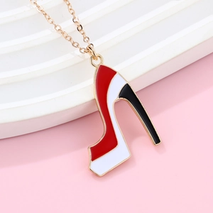Dettaglio di una collana dorata con ciondolo a scarpa con tacco in smalto rosso bianco nero