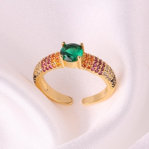Detail of adjustable gold ring with emerald-cut green stone and multi-colored zircons