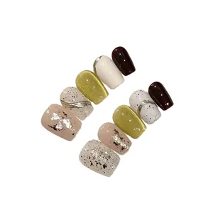 Handmade press-on nails set featuring cat eye effect and gold foil details on white background