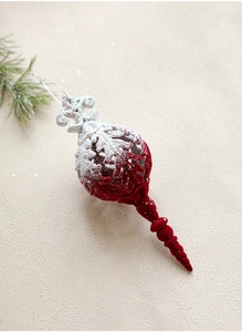 Detail of red and glitter white flocked Christmas ornament on beige textured surface