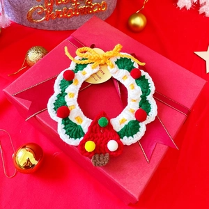 Detail of hand-knitted Christmas wreath pet collar on a red gift box with festive decor