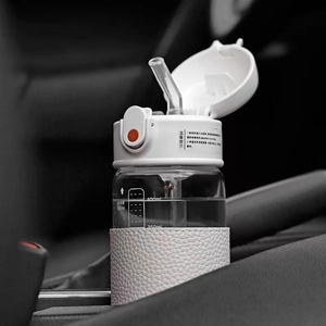 Makroaufnahme einer 500-ml-Glasflasche mit Skala und weißer Lederhülle im Auto