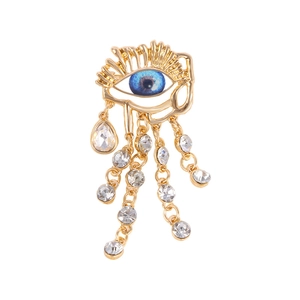 Baroque gold eye brooch with a blue round gem and five elegant crystal tassels
