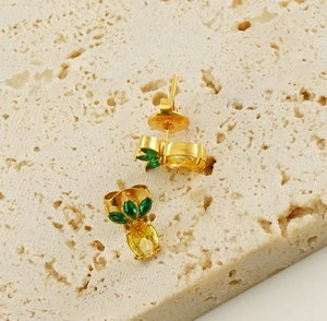 Close-up of gold 18k pineapple stud earrings with green and yellow zircon stones