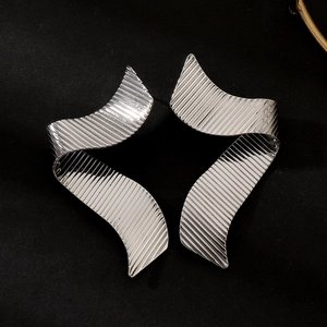 Detailed close-up of silver hoop earrings with textured ripple design on black background