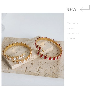Macro view of gold coil bracelets with marquise-cut colorful zircons on stone background