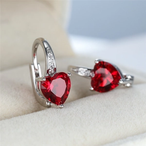 Macro shot of silver stud earrings featuring heart-shaped red rubies and small zircon stones