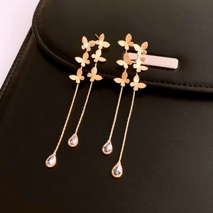Detail of 18K gold-plated butterfly tassel earrings with drop-shaped crystal pendants