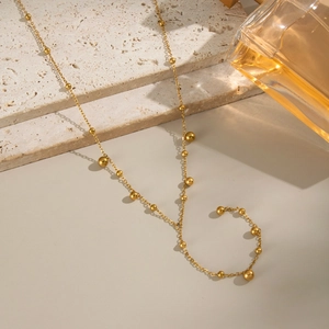 Minimalist 18K gold stainless steel Y-necklace with sphere beads on a textured stone base