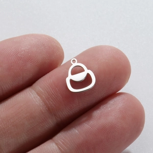 Macro shot of a small silver stainless steel charm pendant held between fingers