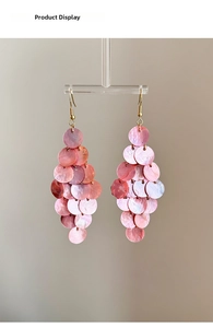 Detail of tiered pink shell tassel earrings with iridescent finish on a display stand