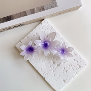 Detail of purple gradient flower hair claw clip with acetate petals on a stone board