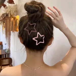 Star-shaped matte hair clips in pink and mauve colors worn on an elegant bun hairstyle