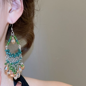 Detail shot of vintage beaded tassel earrings with green and champagne crystal drops