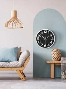 Close-up of a minimalist round wall clock featuring a black dial and white numerals