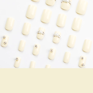 Unghie finte quadrate color crema e giallo con perle eleganti e strass a cuore