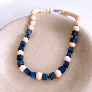 Detailed view of bohemian beaded necklace with white round beads and blue lapis lazuli cubes