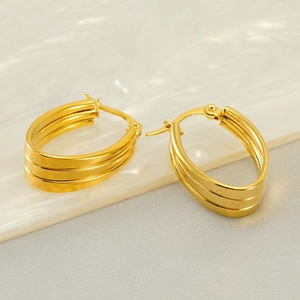 Elegante goldene mehrschichtige ovale Creolen aus Edelstahl auf einer Marmorplatte