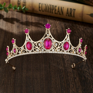 Macro detail of golden crown featuring pink oval gems and clear rhinestones on dark wood