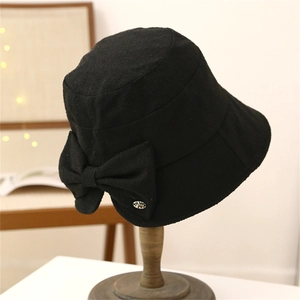 Close-up of black bucket hat texture with a large bow and a small metal logo detail