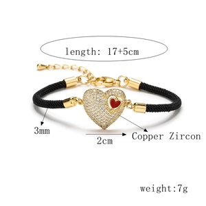 Detail view of gold heart charm with pavé zircon stones on black Milan rope bracelet