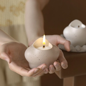 Close-up of cat paw ceramic candle holder with burning wood wick and matte speckle finish