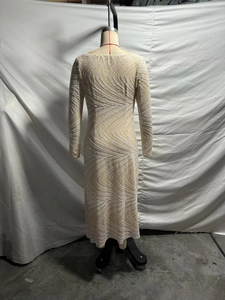 Detail of elegant sequined evening dress featuring intricate wavy patterns and long sleeves