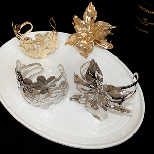 Macro detail of high-gloss gold and silver floral metal bangles on a ceramic plate
