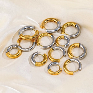 Polished gold and silver titanium hoop earrings in various sizes on silk fabric
