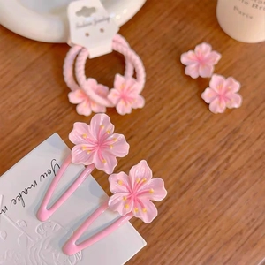 Close-up of pink cherry blossom hair clips and ties on a minimalist wooden table