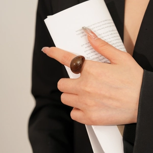 Gros plan d'une bague ovale minimaliste en résine ambre portée par un mannequin
