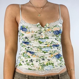 Detailed close-up of lace-trimmed floral tank top featuring delicate buttons and blue flowers