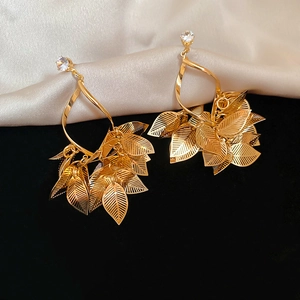 Macro detail of gold leaf tassel earrings with white zircon on elegant velvet and silk