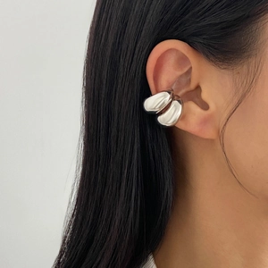 Close-up of a silver C-shaped double-arc ear cuff showing polished metallic texture