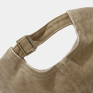 Close-up of vintage khaki cotton baseball cap with adjustable bronze metal buckle and stitching
