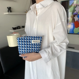 Pochette tissée à carreaux bleus et blancs tenue en main avec texture et fermeture éclair métal