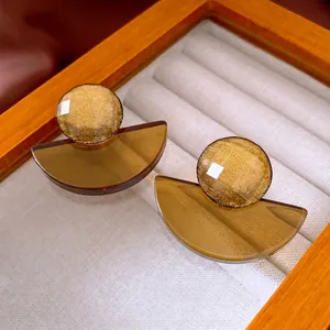 Retro geometric resin drop earrings with gold shimmer tops on a wooden jewelry display
