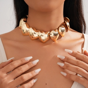 Close-up of chunky gold metallic heart link choker necklace worn by a fashion model