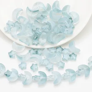 Detailed view of light blue moon and star shaped iridescent glass beads for DIY jewelry