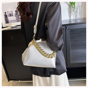 Detail of silver metallic leather handbag with chunky gold chain and retro clasp closure