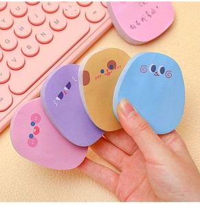 Hand holding cute colorful cartoon animal sticky notes over a pink keyboard background