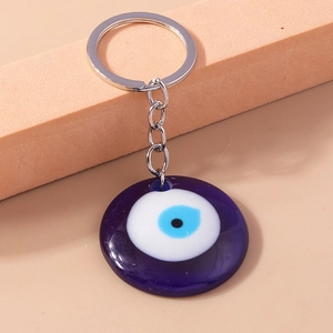 Detail of blue glass Evil Eye keychain charm on orange foam block display